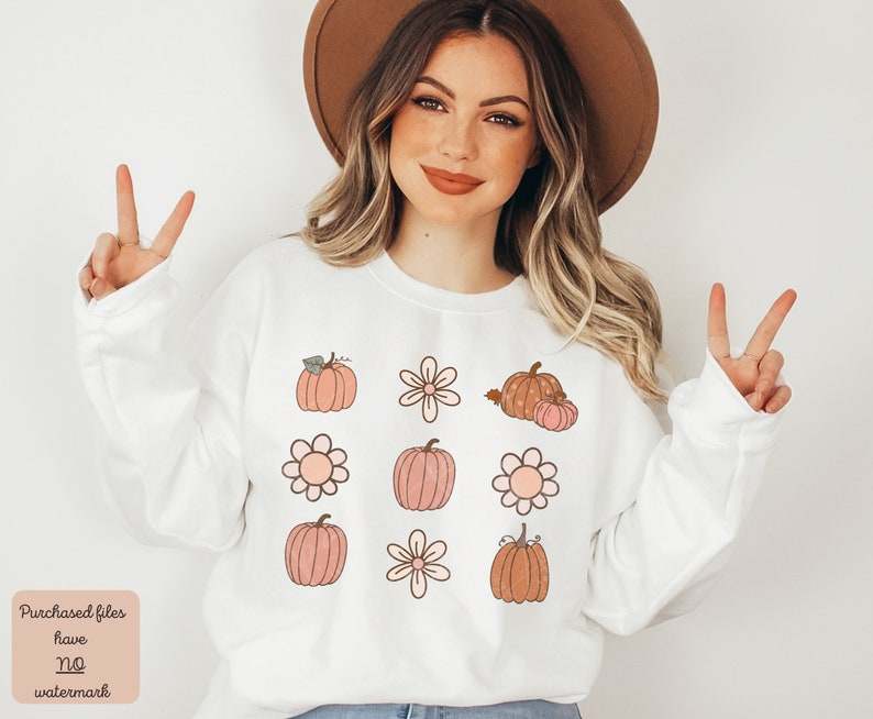Op de afbeelding: Witte trui met een patroon van roze en bruine pompoenen en witte bloemen. De tekst "Purchased files have no watermark" staat onderaan de afbeelding.