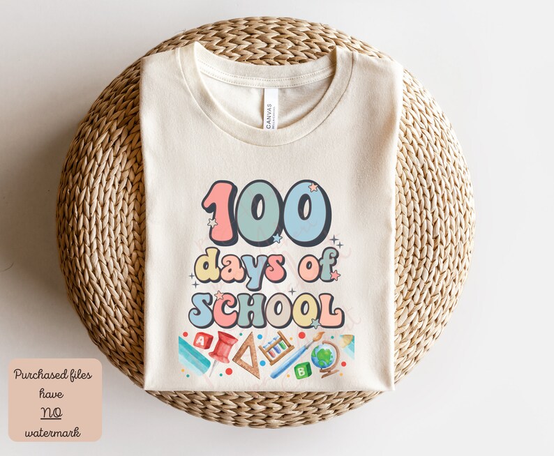 K&ouml;nnte beinhalten: Ein beiges T-Shirt mit dem Text "100 Tage Schule" in bunten, Retro-Lettern. Das Shirt zeigt verschiedene schulthemenbezogene Illustrationen, darunter einen Globus, Bleistifte und ein Lineal.