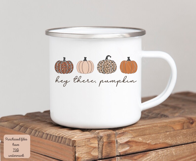 May include: White enamel mug with a handle. The mug has a design of four pumpkins in a row. The pumpkins are orange, brown, and white with a leopard print pattern. The text "Hey there, pumpkin" is written below the pumpkins.