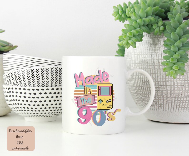 May include: White ceramic mug with a graphic design that says "Made in the 90's" with a retro-style video game controller.