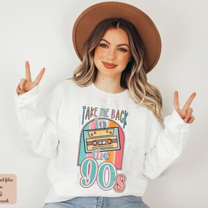 May include: White sweatshirt with a graphic design of a cassette tape and the text "Take Me Back to the 90s". The graphic is in a rainbow color scheme.