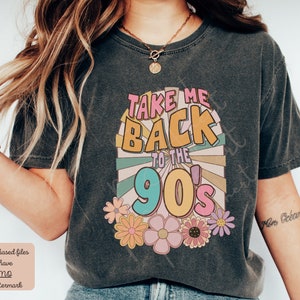May include: A dark gray t-shirt with a retro-style graphic that says "Take Me Back to the 90's" in colorful letters. The graphic is surrounded by colorful flowers.