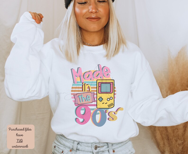 May include: White sweatshirt with a pink, yellow, and blue graphic that says "Made in the 90's" with a retro video game controller.
