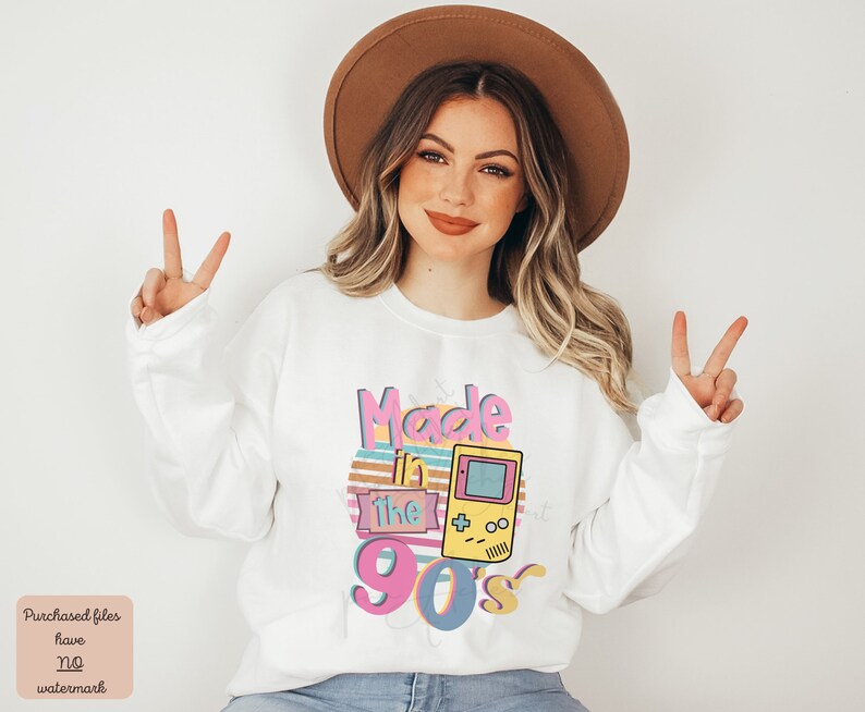 May include: White sweatshirt with a graphic design that says "Made in the 90's" with a retro video game console graphic.