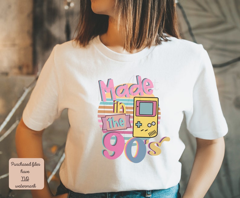 May include: White t-shirt with a graphic design that says "Made in the 90's" with a retro video game console graphic.