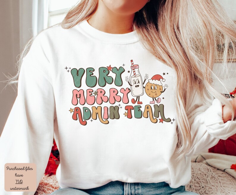 May include: White sweatshirt with a Christmas-themed graphic that says "Very Merry Admin Team". The graphic features a cartoon milk carton and a cookie with Santa hats.
