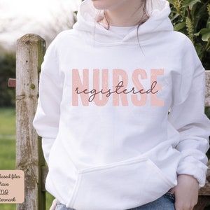 Puede incluir: Sudadera con capucha blanca con el texto "NURSE registered" en letras rosas.