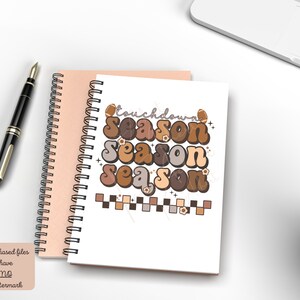 May include: A white notebook with a spiral binding features a brown, orange, and beige graphic design with the text "Touchdown Season" repeated three times. The graphic design includes footballs and flowers.
