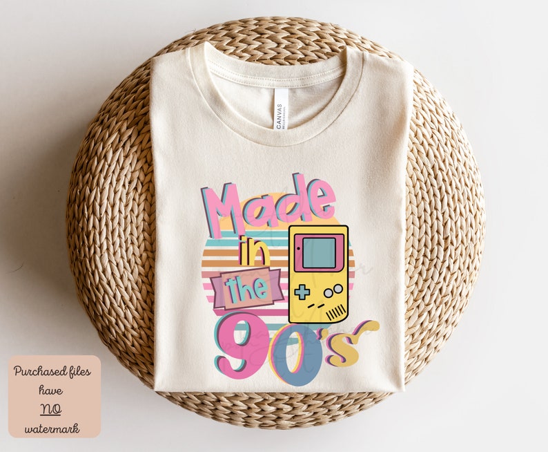May include: A beige t-shirt with the text "Made in the 90's" in a retro font with a colorful sunset and a pixelated video game console graphic.