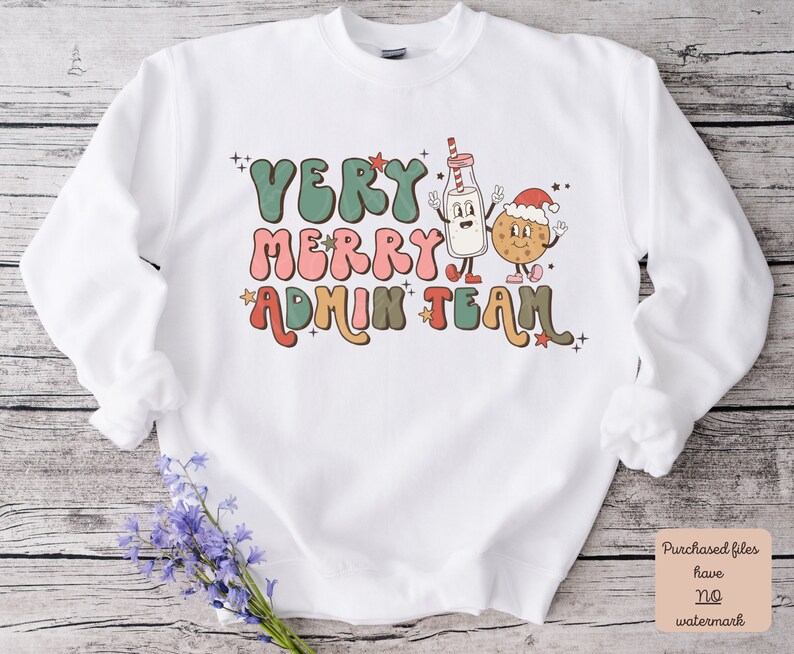 May include: White sweatshirt with a retro-style graphic design featuring a milk carton and a cookie wearing Santa hats. The text reads "Very Merry Admin Team" in colorful, bubbly letters.