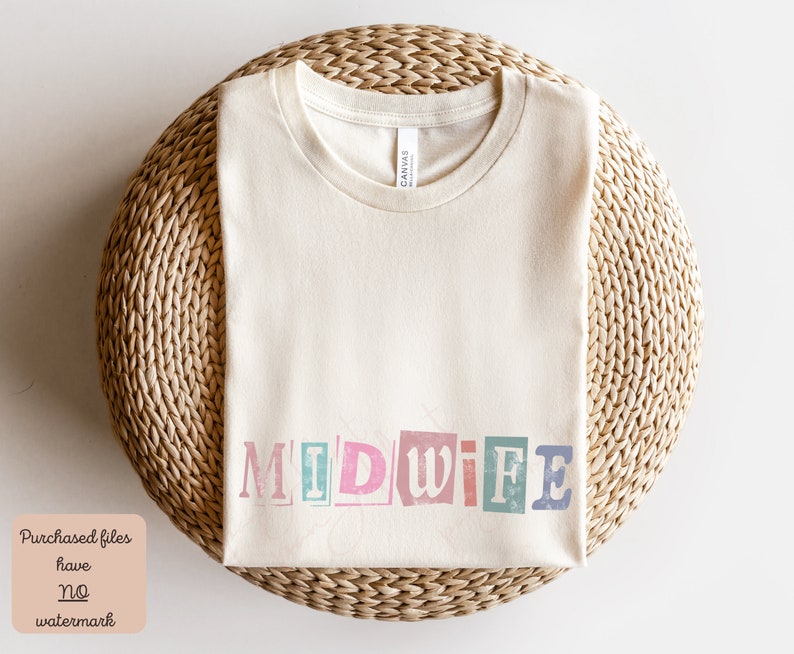 May include: A beige t-shirt with the word "MIDWIFE" printed on it in colorful, distressed letters. The shirt is laid flat on a woven surface.