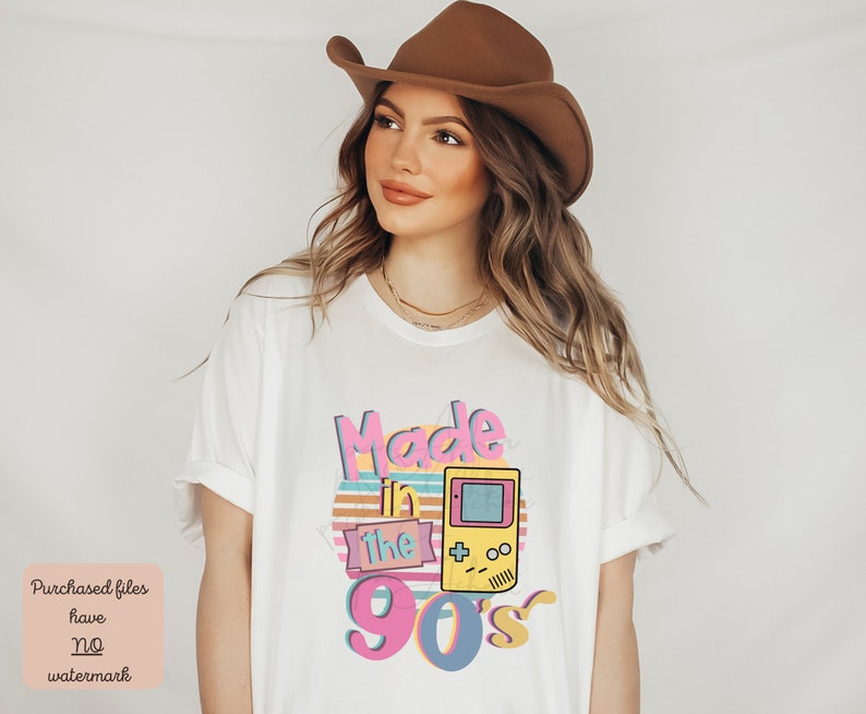 May include: White t-shirt with a graphic design that says "Made in the 90's" with a retro video game controller and a sunset behind it.