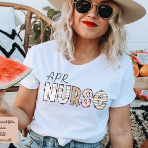 May include: White t-shirt with the text "APR NURSE" in colourful patterned letters. The letters are decorated with pink, brown and white stripes and polka dots.