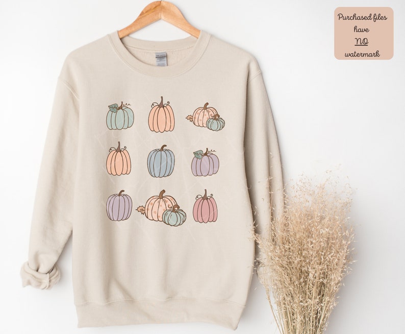 May include: A beige sweatshirt with a graphic of nine pastel colored pumpkins. The pumpkins are arranged in three rows of three.