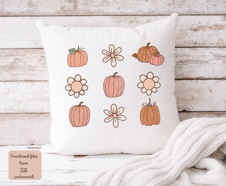 Op de afbeelding: Een wit kussen met een ontwerp van negen herfstthema-illustraties. De illustraties omvatten pompoenen en bloemen in tinten oranje, roze en bruin.