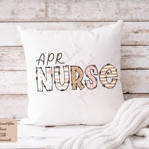 May include: White cushion with the text "APR NURSE" in brown and pink letters with a patchwork design. The letters are outlined in black and have a distressed look.