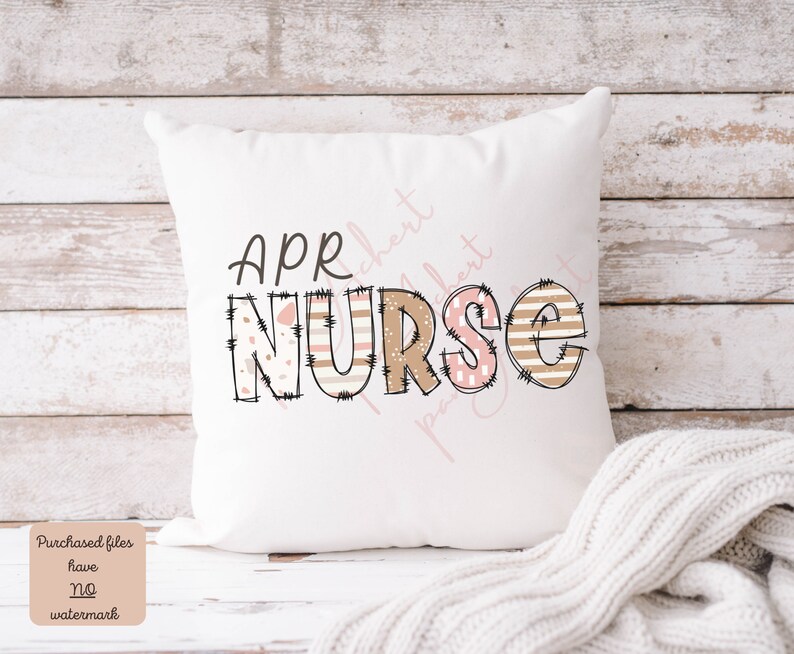 May include: White cushion with the text "APR NURSE" in brown and pink letters with a patchwork design. The letters are outlined in black and have a distressed look.