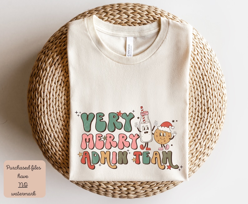 May include: A beige t-shirt with a Christmas-themed graphic that says "Very Merry Admin Team". The graphic features a cartoon milk carton and a cookie with Santa hats.