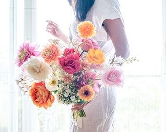 May include: A bouquet of colorful flowers in shades of pink, orange, yellow, and white. The bouquet includes roses, dahlias, and other blooms.