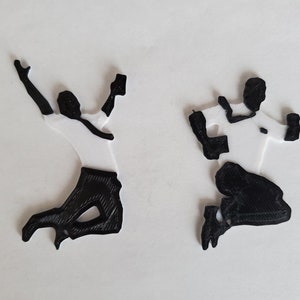 Op de afbeelding: Twee zwart-witte 3D-geprinte figuren van mensen die in de lucht springen.