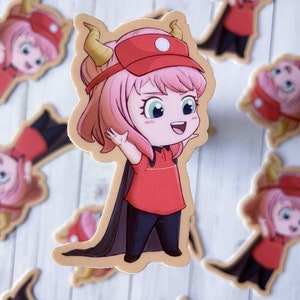 May include: A sticker of a cartoon character with pink hair, wearing a red hat and a red shirt with a black cape. The character has horns and is smiling.