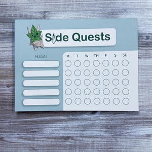 May include: A light blue habit tracker with the words "Side Quests" and a cartoon character illustration. The tracker has space for habits and a weekly calendar with circles for marking progress.