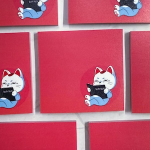 May include: A set of six red sticky notes with a cartoon cat reading a book that says "Death Note".