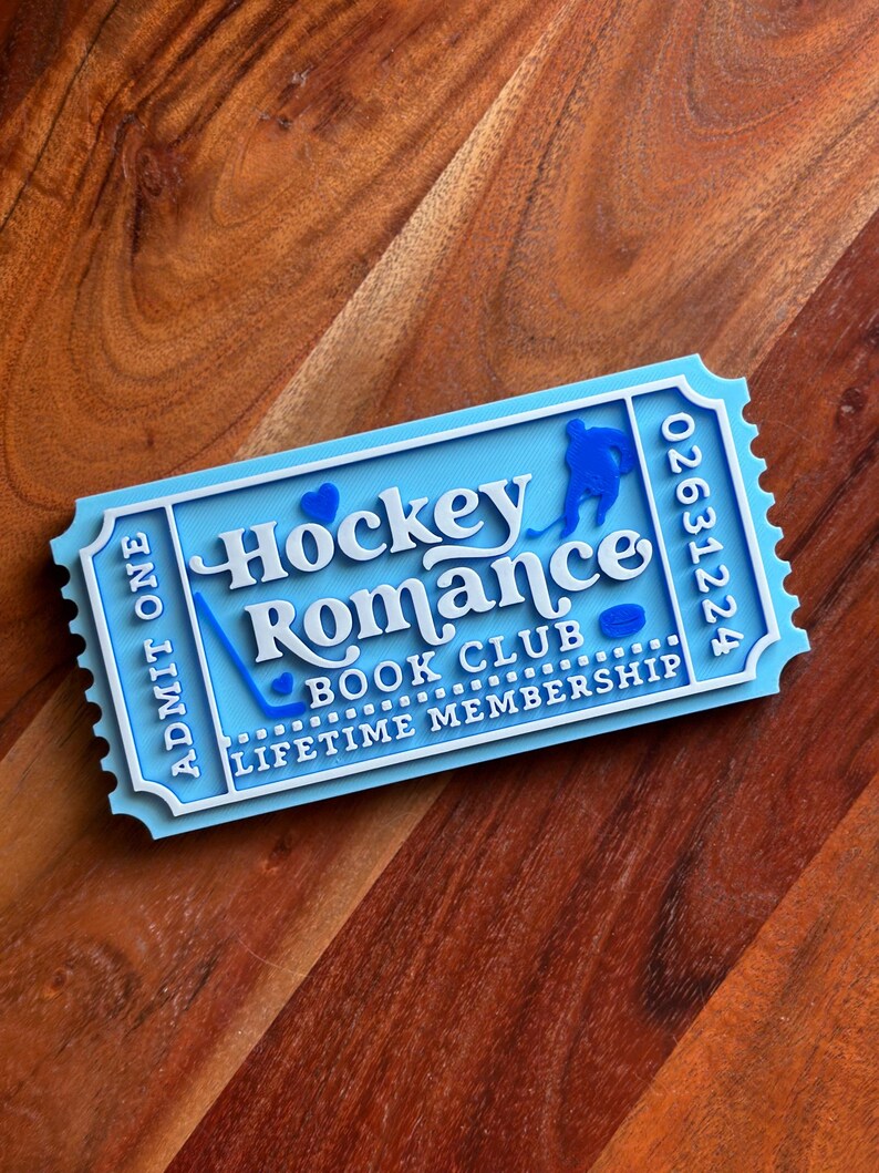 May include: A light blue and white ticket-shaped item with the words "Hockey Romance Book Club Lifetime Membership". The ticket has a hockey player silhouette, a hockey stick, and a puck. The ticket also has the number "02631224".