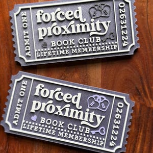May include: Two gray rectangular tickets with white and purple text that read "forced proximity BOOK CLUB LIFETIME MEMBERSHIP". The tickets have a decorative border and the text "ADMIT ONE".
