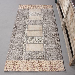 Puede incluir: Una alfombra rectangular con un diseño estampado en marrón y beige. La alfombra tiene un borde floral y un panel central con un patrón geométrico.