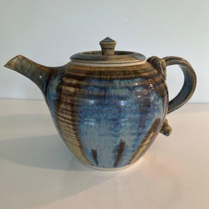 Puede incluir: Un juego de tres tazas de cerámica con un acabado mate moteado. Las tazas son en tonos crema, gris claro y gris oscuro. Cada taza tiene un diseño simple y minimalista y un asa redondeada.