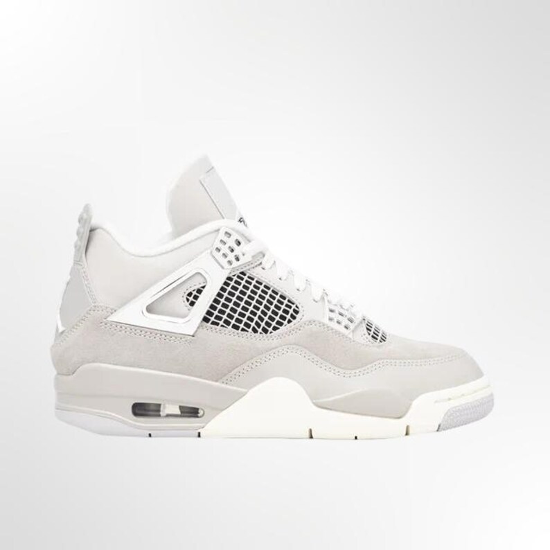 May include: Light grey and white athletic shoe. The shoe features a mesh panel, a white midsole, and a light grey suede upper. The design includes a visible air unit in the heel and a white outsole.