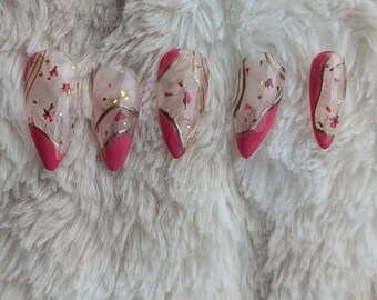 May include: Five pink and clear press-on nails with a gold and pink floral design.