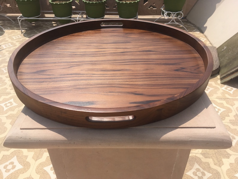 May include: A large, oval wooden serving tray with two handles. The tray is made of dark wood with a rich grain pattern.