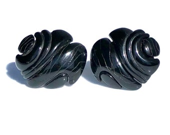 Könnte beinhalten: Ein Paar schwarze, spiralförmige Ohrringe. Die Ohrringe sind aus einem glatten, glänzenden Material gefertigt und haben eine leicht strukturierte Oberfläche.