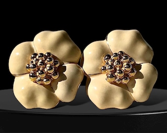 Könnte beinhalten: Ein Paar cremefarbene, blumenförmige Ohrringe mit goldenen Zentren. Die Zentren bestehen aus kleinen, runden goldenen Perlen.
