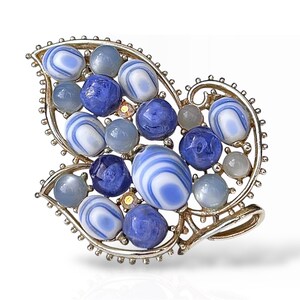 Peut inclure: Une broche argentée en forme de feuille avec des perles de verre bleues et blanches.