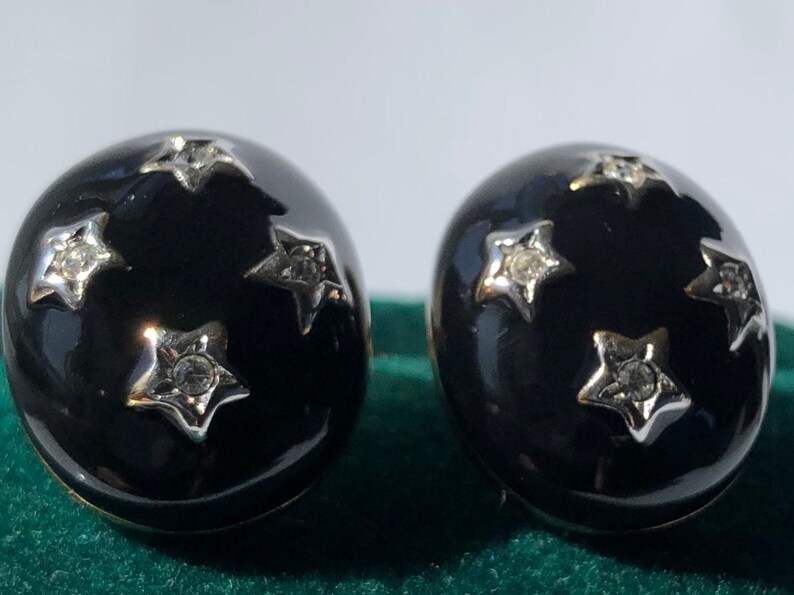 K&ouml;nnte beinhalten: Ein Paar schwarze Emaille-Ohrringe mit silbernen Sternen und Strasssteinen.