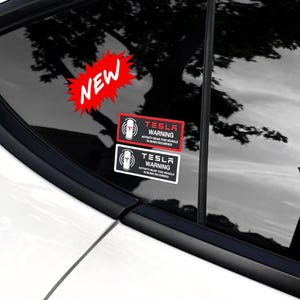 May include: Two black and white warning stickers with red text that say "Tesla Warning" and "Activity near this vehicle is being recorded". The stickers are on a car window with a red "New" sticker on the top left corner.
