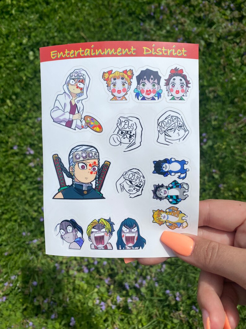 Może przedstawiać: Arkusz kolorowych naklejek z postaciami z anime. Naklejki przedstawiają r&oacute;żne postacie ze szczeg&oacute;łowymi wyrazami twarzy i strojami. Arkusz ma u g&oacute;ry napis "Entertainment District" w kolorze pomarańczowym i białym.