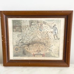 May include: A framed vintage map of Virginia, featuring detailed illustrations and text. The map is in a brown wooden frame, with visible wear on the edges. The map includes the text "VIRGINIA" and "THE VIRGINIAN SEA".