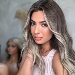 Puede incluir: Una mujer con el pelo largo, ondulado, castaño claro con reflejos rubios. Lleva un top blanco de tirantes y un collar de oro con un colgante redondo.