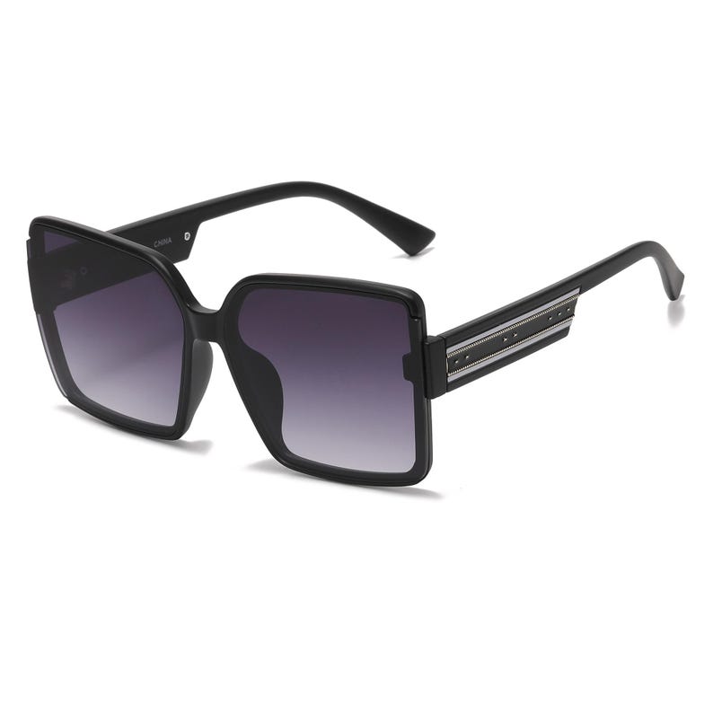 May include: Black square-framed sunglasses with gradient lenses. The sunglasses have a thick frame and a decorative silver stripe with small studs on the temples. The lenses transition from dark at the top to lighter at the bottom.