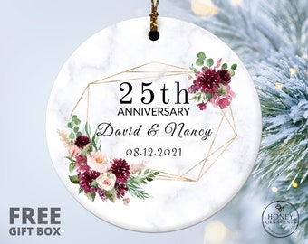 May include: A white marble round ornament with a gold geometric frame and burgundy and blush floral design. The text "25th Anniversary David & Nancy 08.12.2021" is inside the frame.