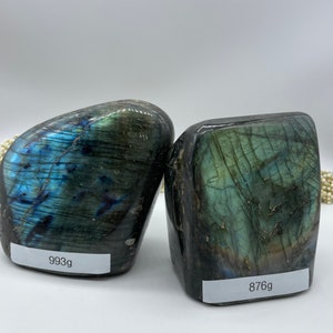 Könnte beinhalten: Zwei große, dunkelgrüne Labradorit-Steine mit irisierenden blauen und grünen Schimmern. Die Steine sind glatt und poliert. Der Stein links wiegt 993 Gramm und der Stein rechts wiegt 876 Gramm.
