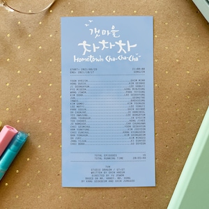 May include: A blue card with white text listing the cast and crew of the Korean television series "Hometown Cha-Cha-Cha". The title of the show is written in Korean and English. The card also includes the start and end dates of the show, the total number of episodes, and the total running time.
