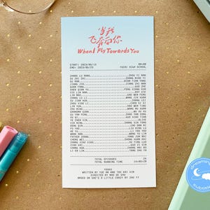 May include: A white card with pink and red Chinese characters that translate to "When I Fly Towards You". The card lists the cast and crew of the show, including the start and end dates of filming. The card also includes the total number of episodes and the total running time.