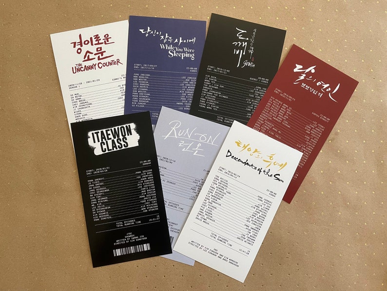 Puede incluir: Una colecci&oacute;n de seis tarjetas impresas en blanco y negro con los t&iacute;tulos de populares dramas coreanos: "The Uncanny Counter", "While You Were Sleeping", "Goblin", "Itaewon Class", "Run On" y "Descendants of the Sun".