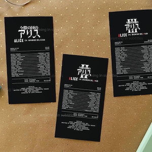 May include: Three rectangular black cards featuring white text detailing the cast and production credits for the series Alice in Borderland. Each card displays the show title in Japanese and English, episode lists, and technical production data.