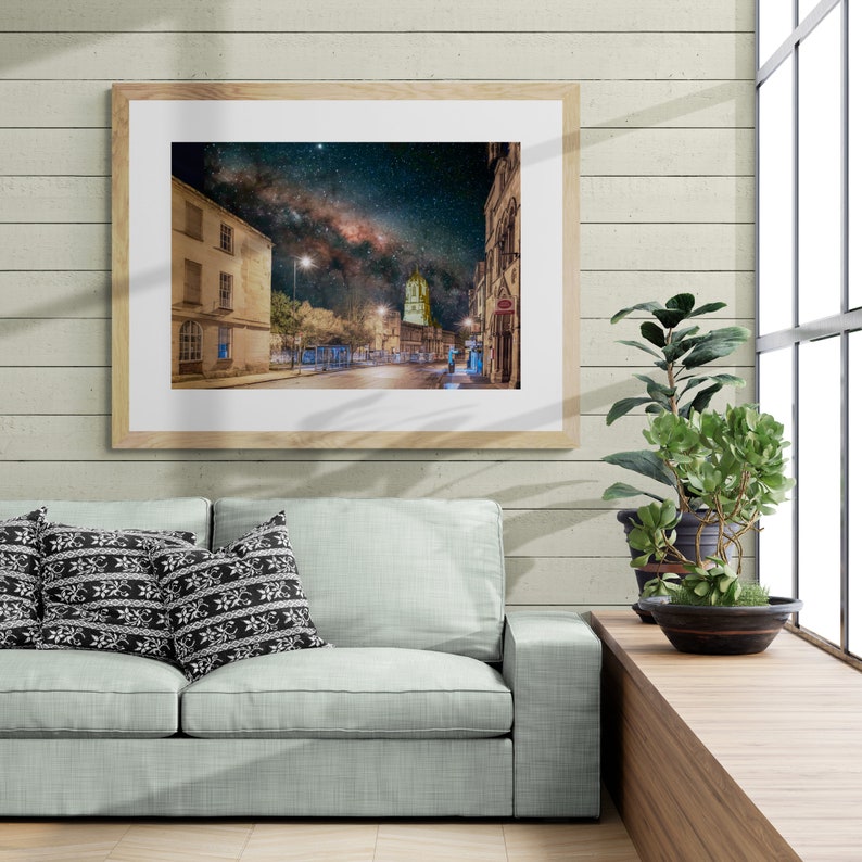May include: A framed photograph of a city street at night with the Milky Way visible in the sky. The street is lined with buildings and streetlights.